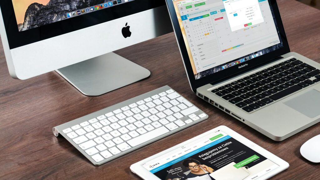 Web-Entwicklung: Win moderner Büro-Schreibtisch-Setup mit Apple-Geräten: iMac, MacBook, und iPad.